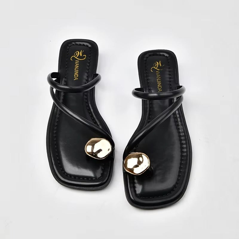 Black sandals with gold accents on a white background